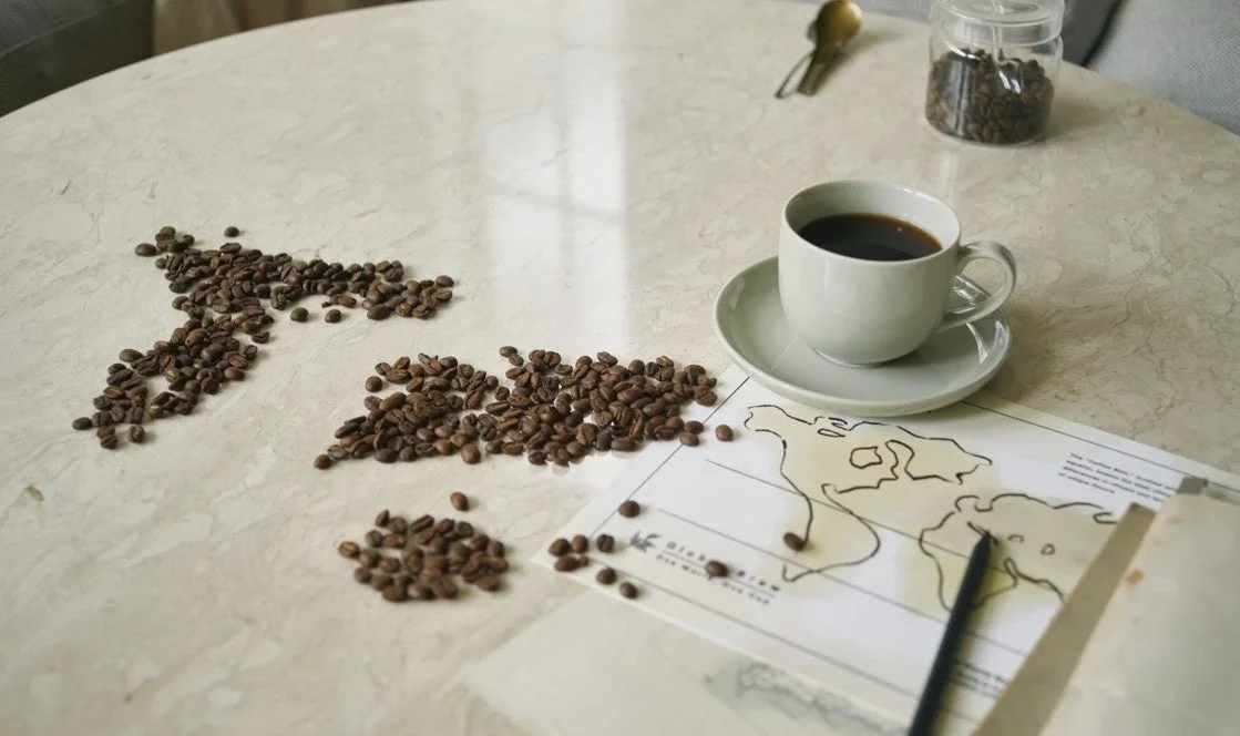 産地を味わうコーヒーのコーヒー豆とカップ、世界地図の資料