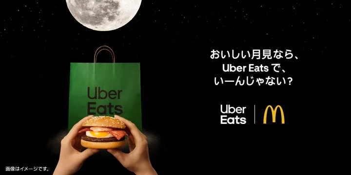 月夜を背景にUber Eatsの紙袋とマクドナルドの月見バーガーを持つ手、キャンペーンロゴの広告画像