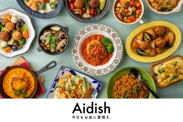 「Aidish」のロゴと、彩り豊かな様々な冷凍宅配食のメニューが並べられた食卓