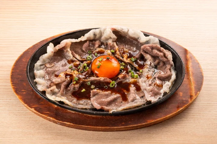 鉄板に盛り付けられた黒毛和牛の焼しゃぶと卵黄