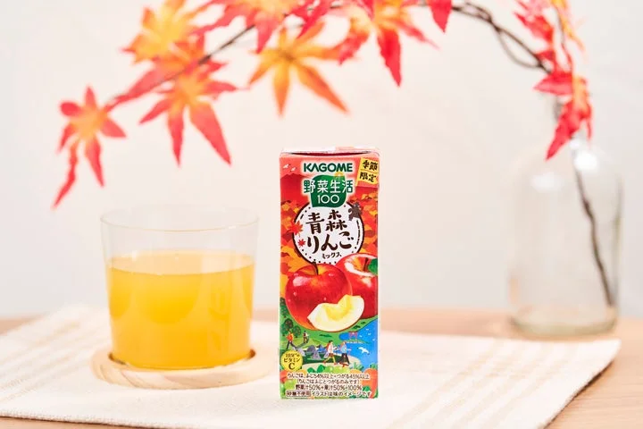 グラスに入った野菜生活100青森りんごミックスと、紅葉の枝が飾られたテーブルの様子