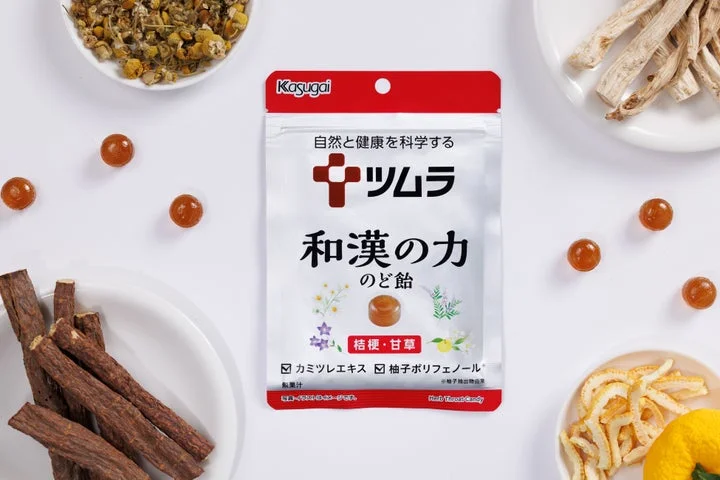 ツムラのど飴のパッケージと、桔梗、甘草、カミツレ、柚子の原材料が並んでいる様子
