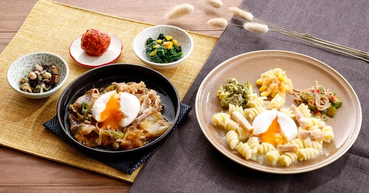 半熟卵のカルボナーラショートパスタと牛すき、および副菜が並んだ食事のセット
