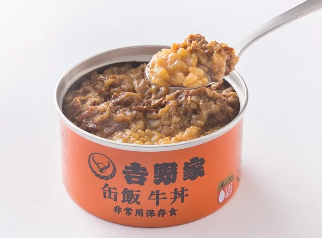 開封された吉野家「缶飯 牛丼」の中身をスプーンですくっている様子