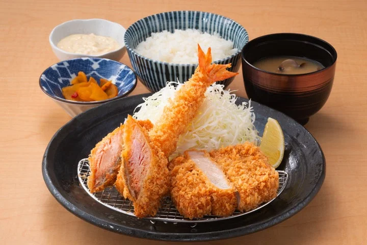 ロースかつと秋鮭フライ、海老フライが盛り付けられた定食セット