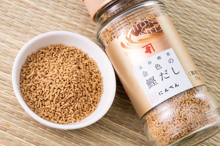瓶に入った顆粒状の「金色の鰹だし」と、小皿に盛られた顆粒だし