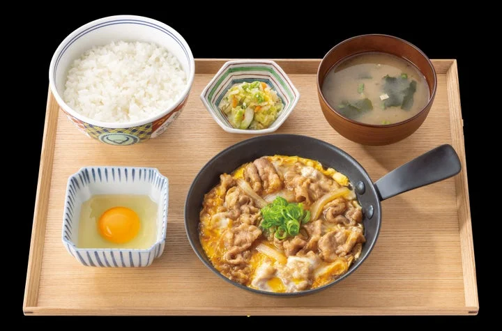 鉄鍋に入った牛とじ、ご飯、みそ汁、漬物、生卵がセットになった月見牛とじ御膳