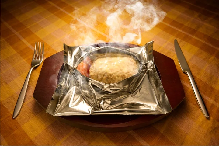 湯気が立ち上るチーズソースの包み焼きハンバーグ