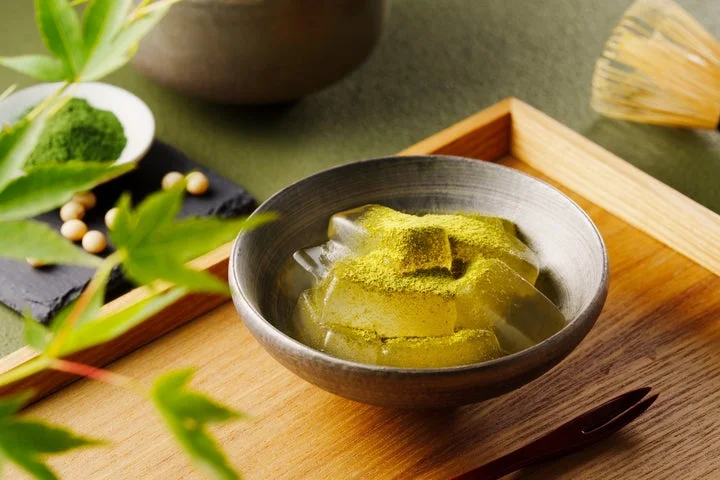 抹茶パウダーがまぶされた蒟蒻Pururiが器に盛られ、茶筅が添えられたイメージ画像