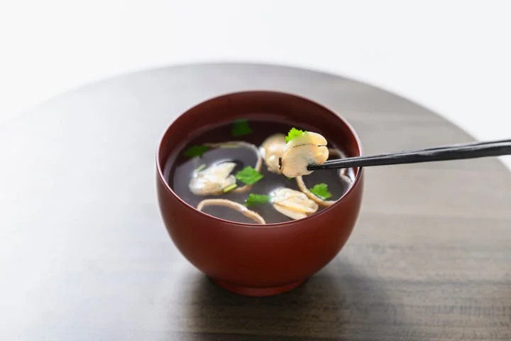 箸で持ち上げたはまぐりの身が入ったお吸い物