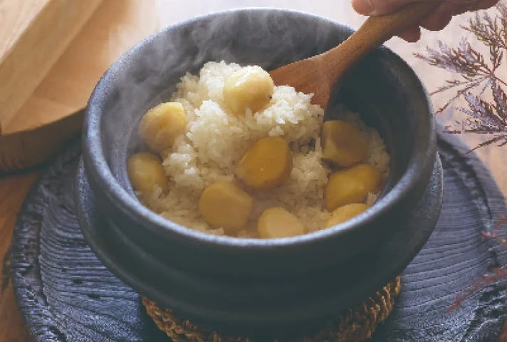 土鍋で炊き上がった栗ごはんを木べらで混ぜている様子