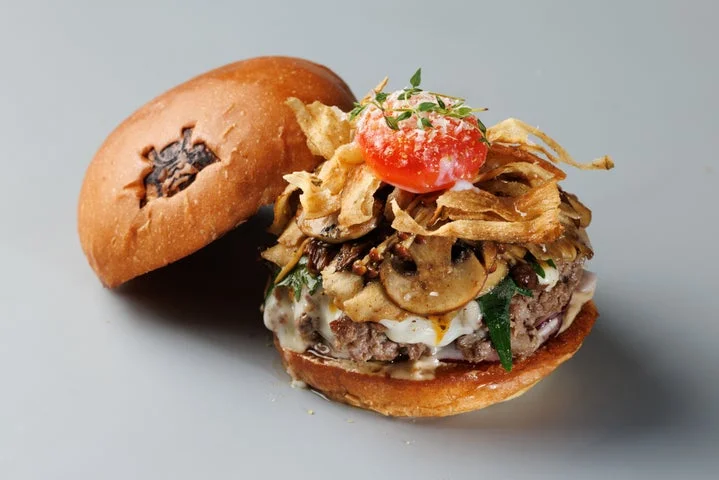 黄身のコンフィとキノコをトッピングした月見バーガーのアップ
