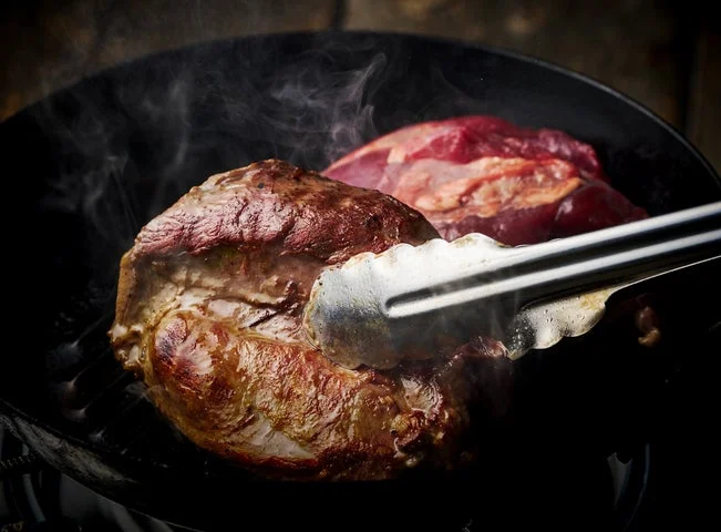 フライパンで猪肉を焼き上げる調理風景