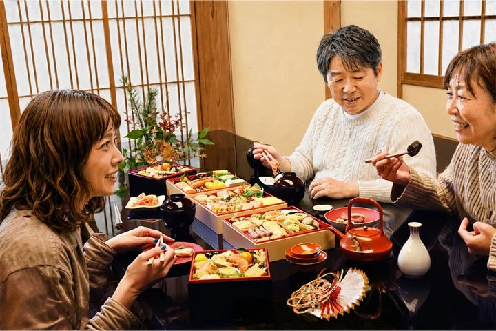 家族が食卓でおせち料理を囲んで楽しんでいる様子