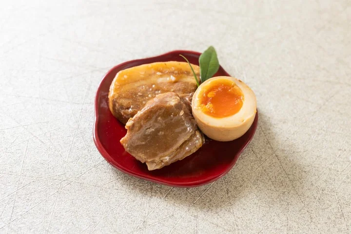 赤い小皿に盛られた豚のとろ角煮と煮たまご
