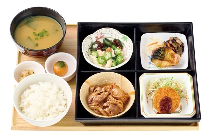 黒い重箱に4種のおかず、柿の形の団子、ご飯、味噌汁が並ぶ秋の季節御膳