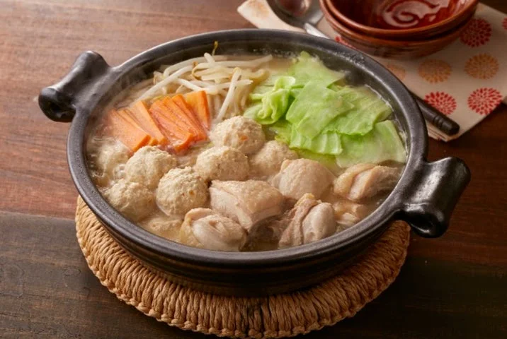 黒い土鍋に入った鶏肉とつみれ、野菜の味噌鍋