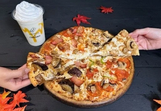 木製トレイに載せられた4種のトッピングが異なるピザと、ホイップクリーム付きのシェイク