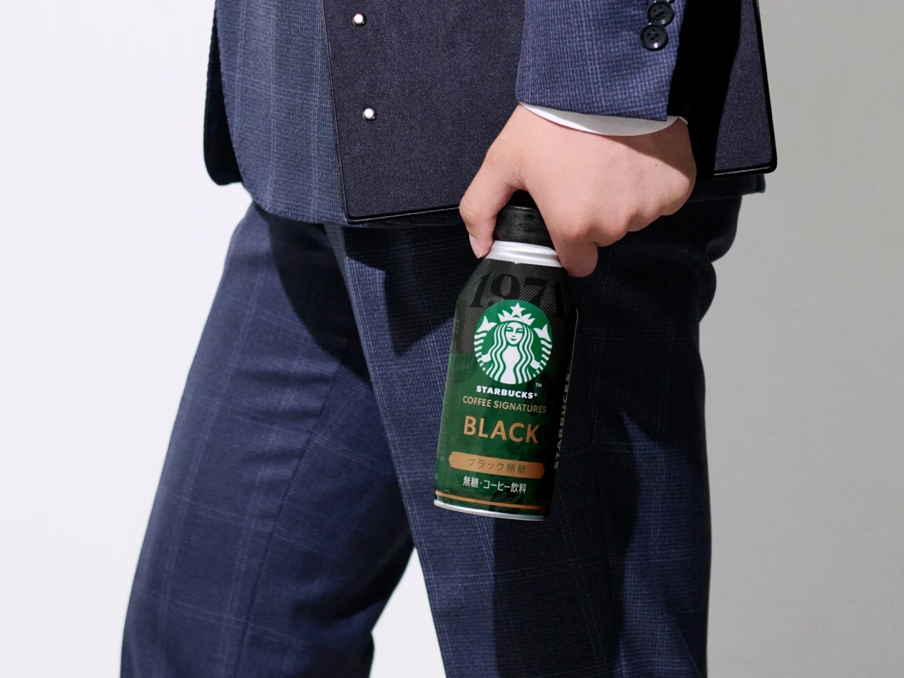 スターバックス® COFFEE SIGNATURES BLACKの缶を手にした人物