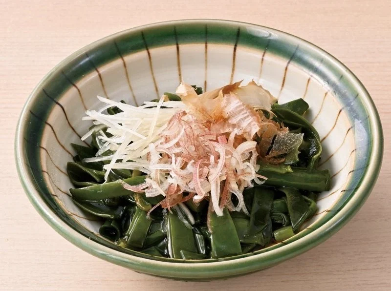三陸産 めかぶぽん酢。緑のめかぶに白髪ねぎと削り節を添えた器