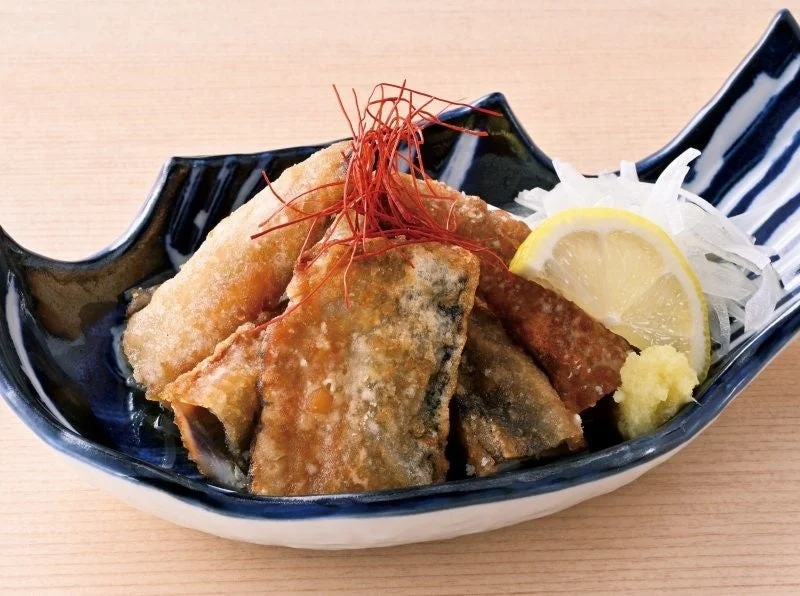 いわしの南蛮風。揚げた魚の切り身とレモン、薬味を盛り付けた料理
