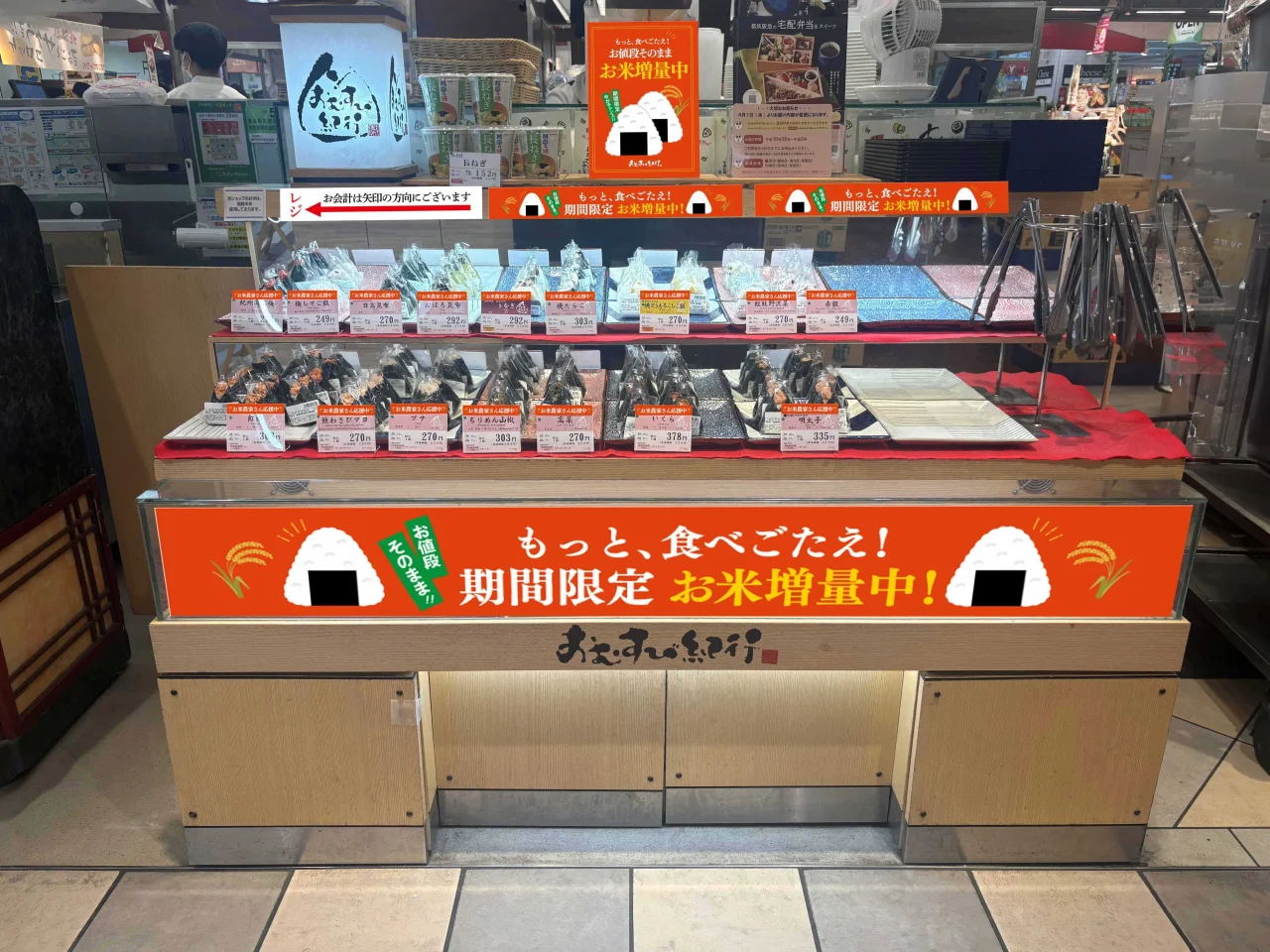 おむすび紀行店舗の陳列棚と、期間限定お米増量中を示すオレンジ色の看板