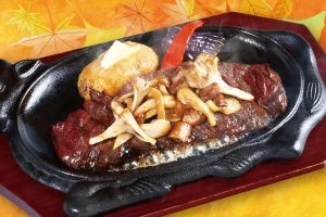 4種の茸のハラミステーキ。黒い鉄板に盛り付けられた肉とキノコ類。