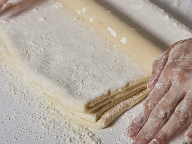 パイ生地を麺棒で伸ばしている製造工程