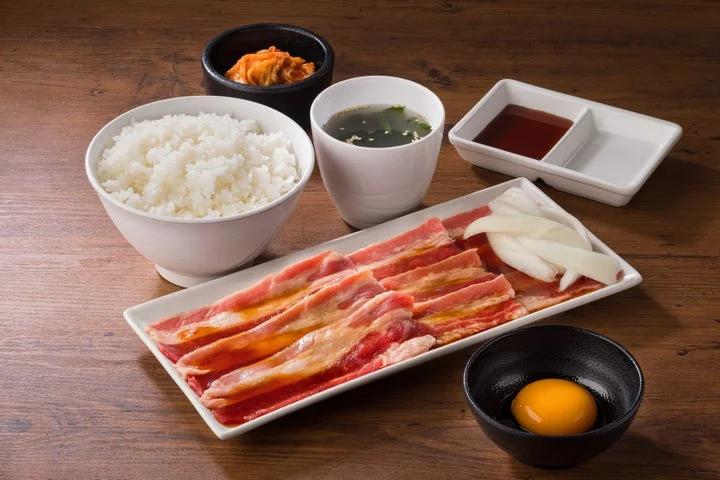 月見大判カルビセット。大判カルビ、生卵、ごはん、スープ、キムチが並んでいる。