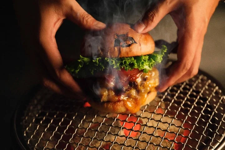 網の上で焼かれ、湯気が上がる和牛ハンバーガー