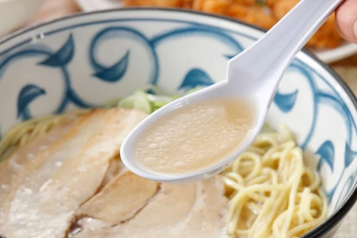 レンゲですくった牛骨塩ラーメンのスープ