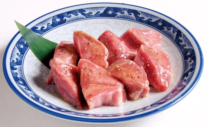 青い波模様の皿に盛られた厚切りの生豚タン