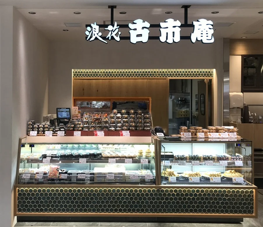 古市庵の店舗内観。冷蔵ショーケースに寿司やおむすびが並び、上部に店名看板が設置されている。