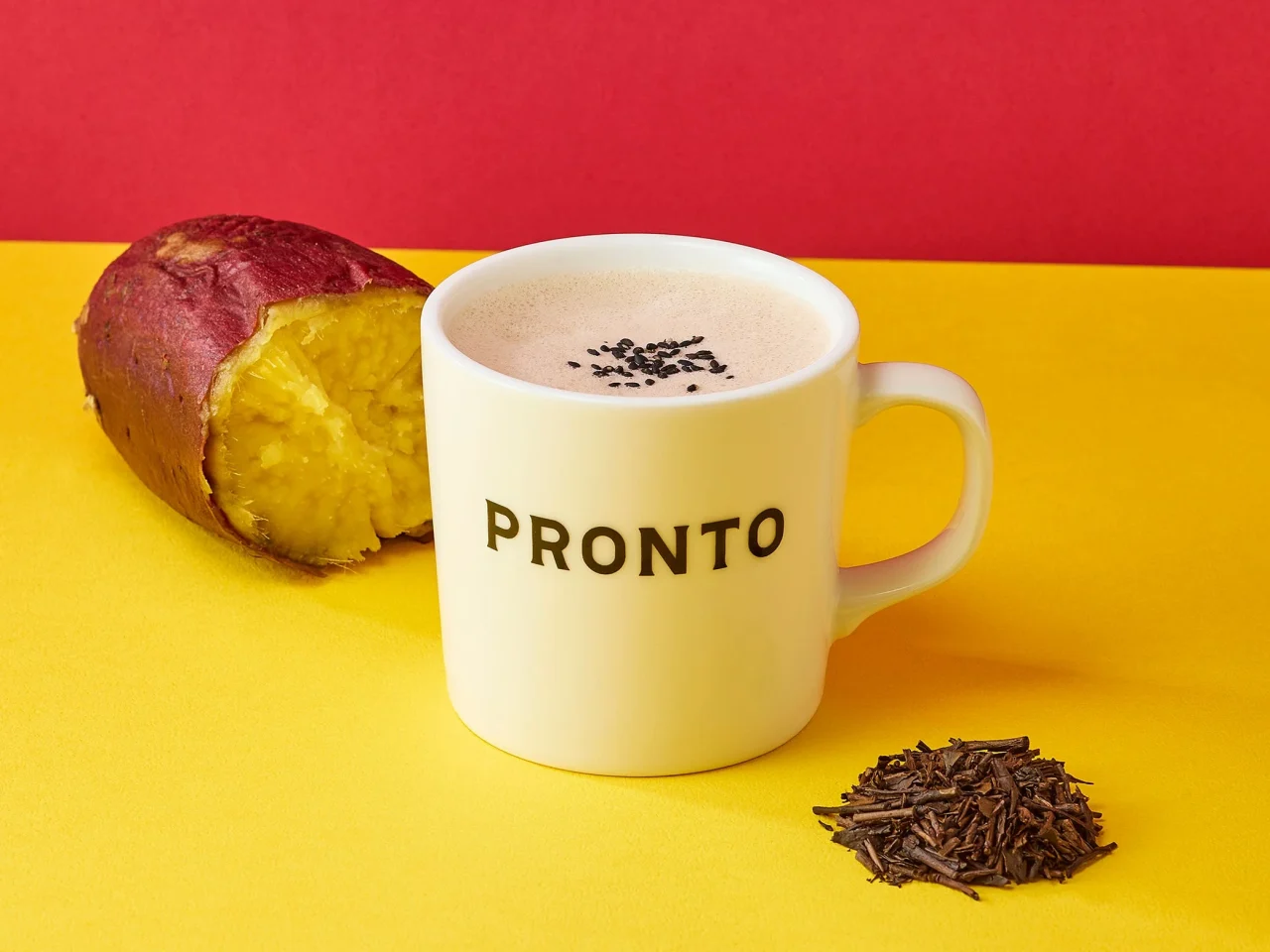 お芋ほうじ茶ラテ。PRONTOロゴ入りの白いマグカップに注がれたラテと、さつまいも、ほうじ茶の葉が写る。