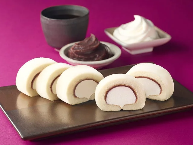 皿に盛り付けられた断面が見えるロールケーキと、あんこ、クリーム