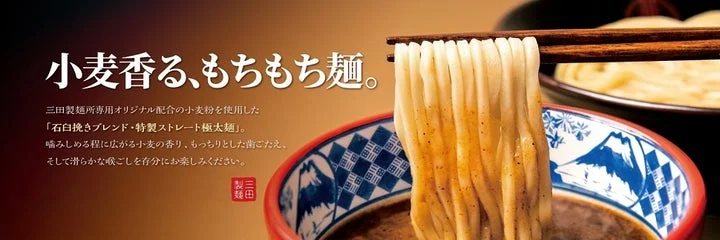 箸で持ち上げられた極太麺と濃厚なつけ汁