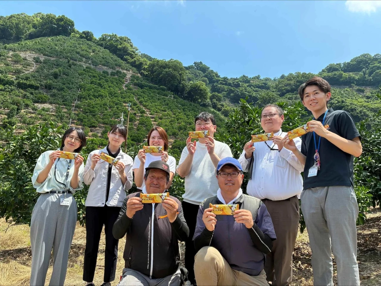 みかん畑で「とろける食感 ぎゅっとみかん」を手にする人々