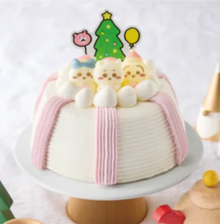 クリスマスかまくら。白いホイップクリームで覆われたケーキに、ピンクのリボンとクリスマスツリーの飾りが添えられている。