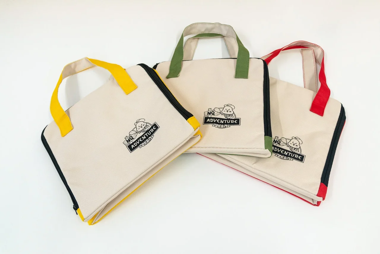 保冷ランチバッグの3色展開。ベージュ地にキャラクターとロゴがプリントされた手提げ型。