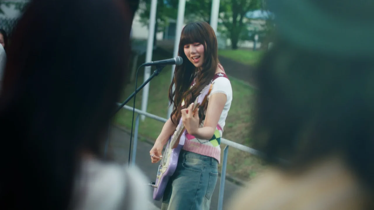 カンデミーナグミ新WEB CMに出演するふみのさんが屋外でギターを演奏する姿