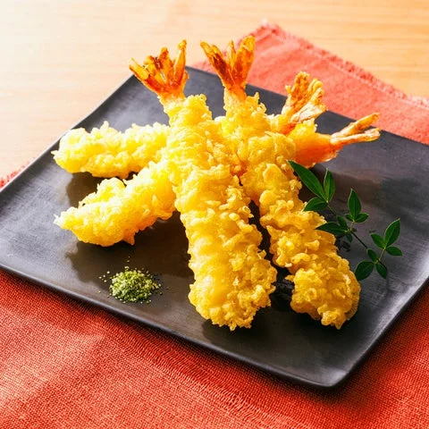 黒い皿に盛り付けられた、衣がサクサクした見た目のえび天ぷら