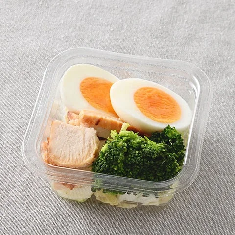 透明な容器に入ったチキン、ゆでたまご、ブロッコリーのサラダ