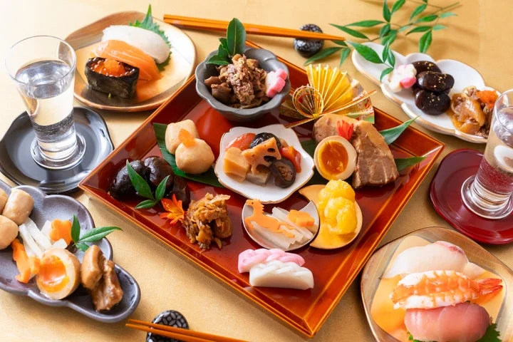 おせち料理や寿司、飲み物が並んだ華やかなお正月の食卓風景