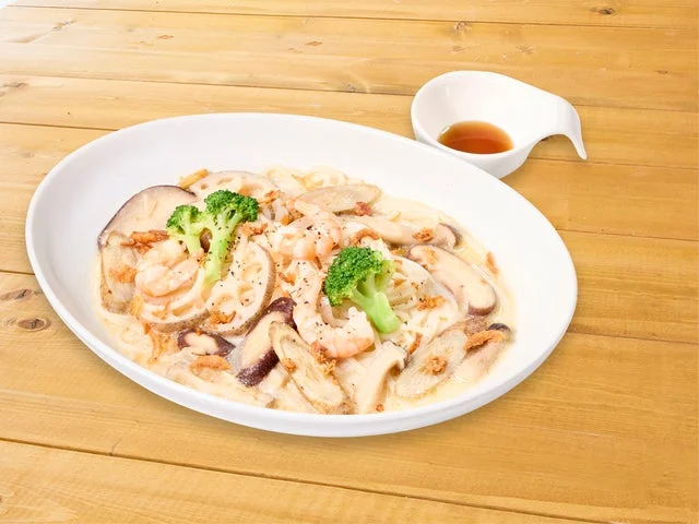海老、ブロッコリー、根菜が入った白いスープのヌードル料理