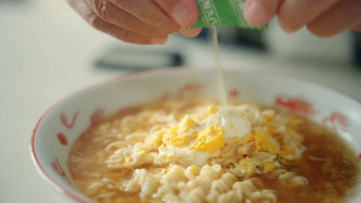 卵が乗った醤油ラーメンにスパイスを振りかける手元