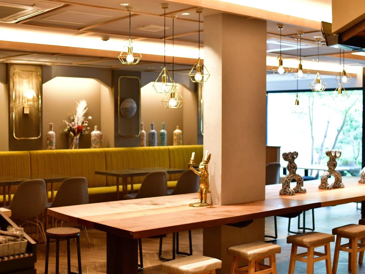 MICASADECO&CAFE 京都の店内。木製テーブルと黄色いソファ席、幾何学模様の照明が並ぶ。