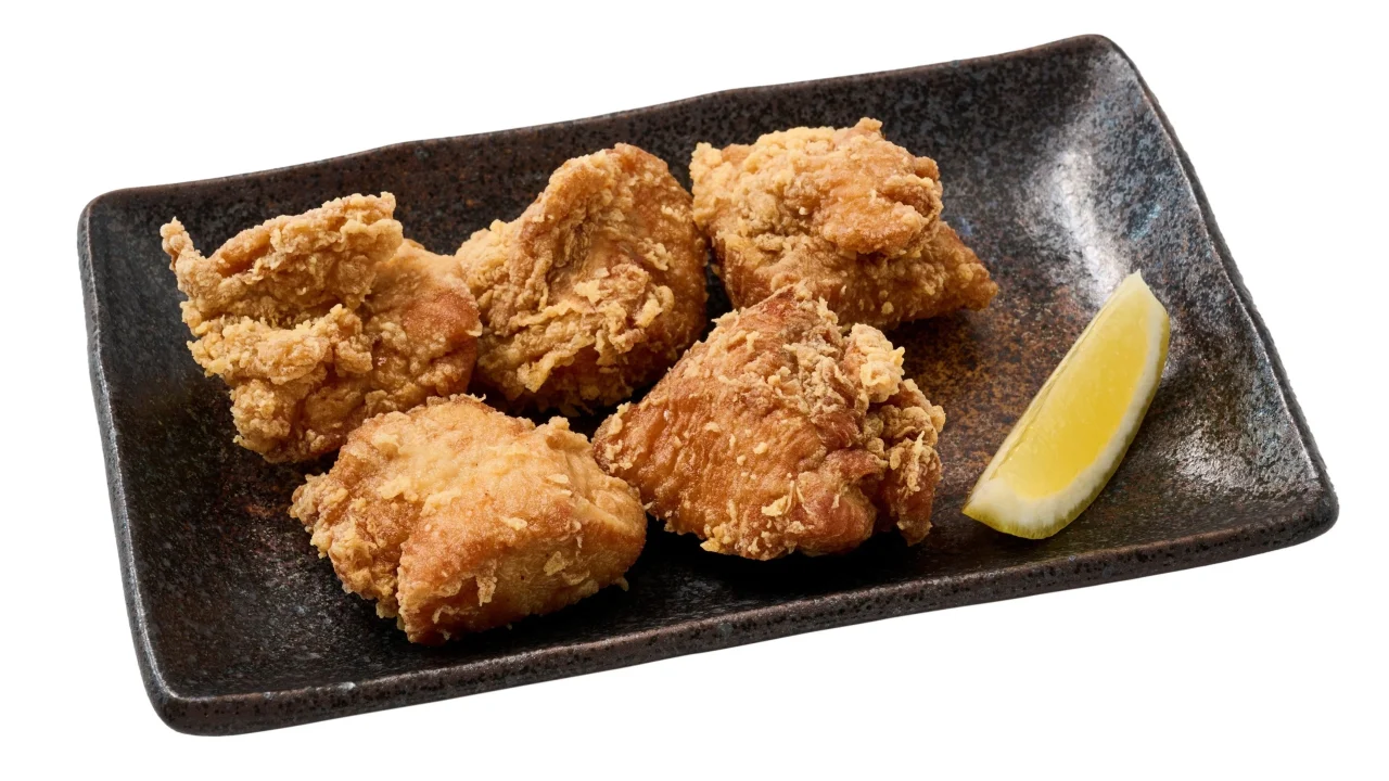 鶏むねのから揚げ5個とレモンを黒い長皿に盛り付けた写真