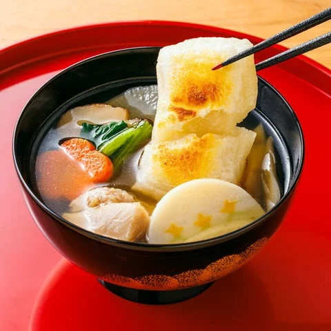お椀に入ったお雑煮。焼き餅、人参、かまぼこ、青菜が見える
