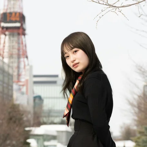 黒いトップスとカラフルなスカーフを首にかけた女性えながさんの屋外ポートレート
