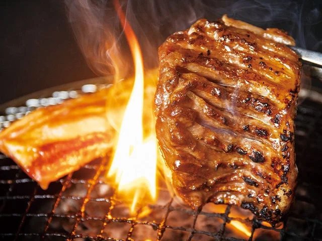 炭火の炎で焼かれる肉と網のクローズアップ